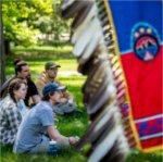 students sit in circle, Native banner with feathers at right